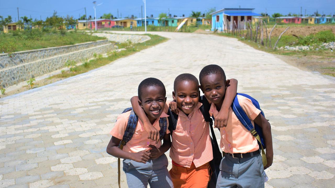 三个小男孩站在海地新开发的住房前